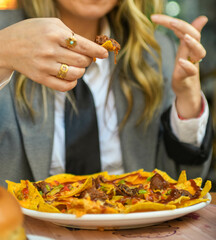 Mujer joven comiendo nachos con queso en un restaurante. Concepto de comida rápida.