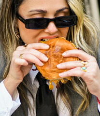 Una joven empresaria comiendo una hamburguesa en un café al aire libre