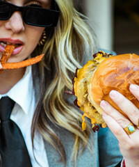 Una joven empresaria comiendo una hamburguesa en un café al aire libre