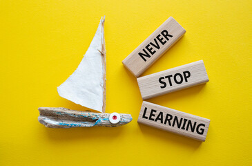 Never stop Learning symbol. Concept words Never stop Learning on wooden blocks. Beautiful yellow...