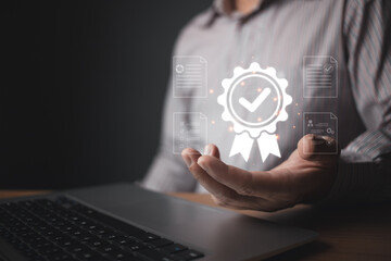 A person holds a glowing quality control badge hologram featuring a checkmark and surrounding digital document icons, symbolizing certification, standards, and reliable assurance in modern processes.