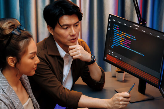 IT developers discussing with point to intelligent website development coder system running data online two screens information technology at neon light room at modern office. Infobahn.