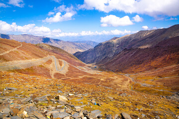 Winding road among the yellow grass, Babusar Pass. Beautiful autumn landscape in Karakoram mountains, Pakistan. 