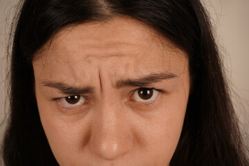 A young woman with furrowed brows displays an expression of seriousness. Her intense gaze reflects...