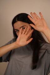 It highlights the theme of domestic violence. A woman holds both hands in front of her face, a defensive posture expressing fear and protection. The gesture symbolizes the instinctive response to