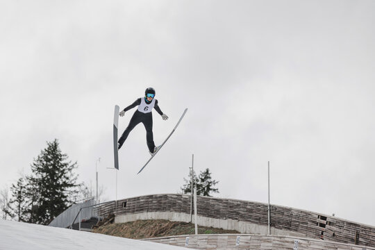 Professional male athlete performing ski jumping, flying through the air during training.