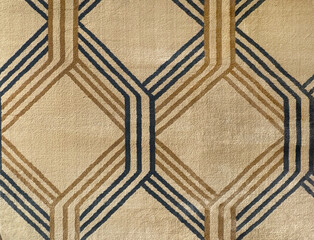 Close up of carpet rug fabric in weaving diamond pattern and lines. In brown, gold, and beige...