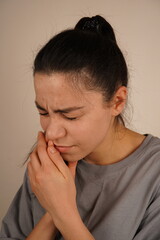 Her body language reflects physical discomfort. The moment is a genuine depiction of personal unease. The woman clutches her gum with a pained expression, capturing the sensation of a toothache.