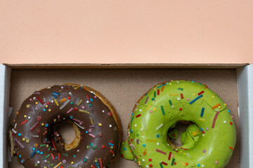 Donuts in box on beige background. Closeup.