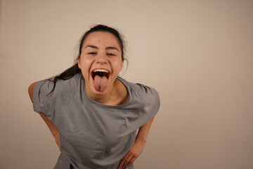 With a playful expression, the girl sticks her tongue out towards the camera in a silly gesture. Her face is full of fun, capturing a light and humorous moment. It is a fun and playful reaction.