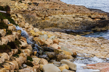 Rocky Coastal Cliff Overlooking Clear Blue Ocean with Small Structures