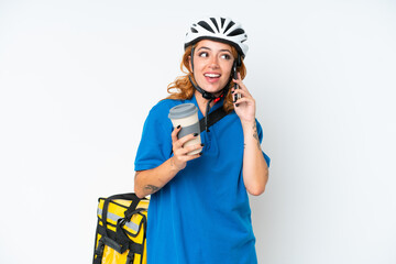 Young caucasian woman with thermal backpack isolated on white background holding coffee to take away and a mobile