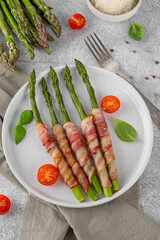 Baked green asparagus with bacon and parmesan cheese on a plate. Healthy food. Top view