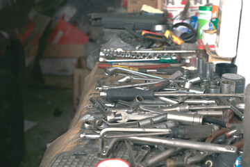 Assorted tools and wrenches on a cluttered workbench in an auto repair shop