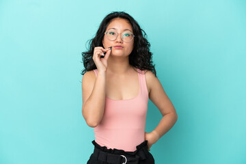 Young asian woman isolated on blue background showing a sign of silence gesture