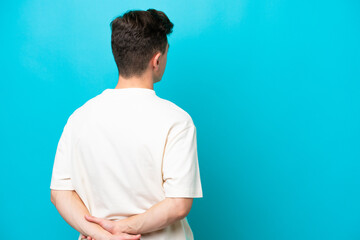 Young handsome Brazilian man isolated on blue background in back position and looking back
