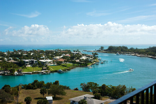 View from Lighthouse Overlooking Jupiter Inlet, Florida. Sunny day blue sky and white clouds. Boats in water with small wakes. Scenic intercoastal waterway.