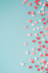 Candies hearts of pastel colors on blue paper. Flat lay. 
