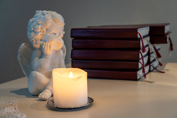 Angel Figurine and Candlelight with Books. Peaceful Scene with Angel Sculpture and Candle.