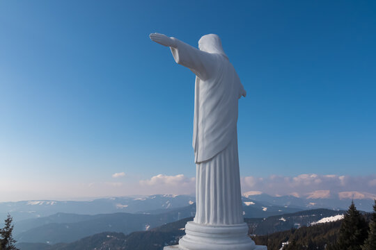 Christ the redeemer statue on Gleinalm in Styria, Austria, Europe. Monument surrounded by forest and Lavanttal Alps. Winter wonderland. Ski touring. Faith, freedom concept. Terenbachalm, Austrian Alps