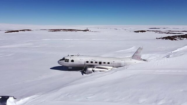 Broken abandoned plane covered in snow. Wreckage of the russian plane left in Antarctica. Old scientific station on South pole. Ecological disaster. Pollution of the Earth. Aerial shot.