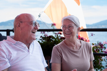 Senior cheerful couple sitting at restaurant table enjoying a sunny day on Lake Geneva, Tourism,...