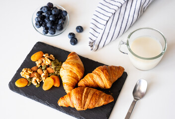 Breakfast concept. French fresh croissants, dried and fresh fruit, blueberries and milk