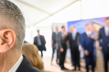 unrecognizable businessman in blue suit speaks into microphones at event