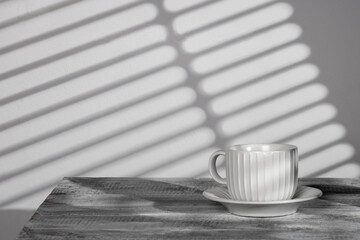 A white cup with a matching saucer sits in the corner, adding a touch of elegance and simplicity....