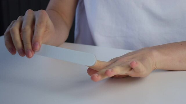 White European woman filing her nails. Home manicure close-up. Beauty care