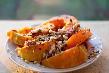 Baked pumpkin pieces with honey and walnuts in a plate. Delicious healthy dessert.