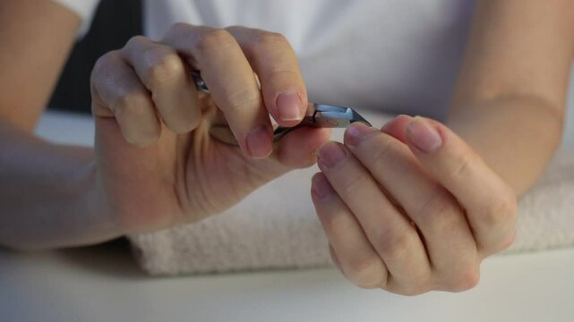 White European woman doing her manicure. Hands with cuticles close-up. Home manicure