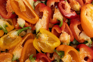 Top view of vibrant red, orange, and yellow bell peppers in a roasting tray lined with foil, seasoned and ready for baking. healthy meal preparation and cooking.healthy eating
