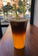 Iced coffee in a plastic cup on a wooden table in a cafe