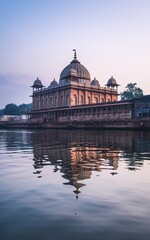 Obraz premium Calm dawn reflection of a riverside Mughal-style mausoleum.
