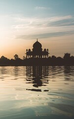 Fototapeta premium Silhouette of a mausoleum reflected in calm water at sunset.