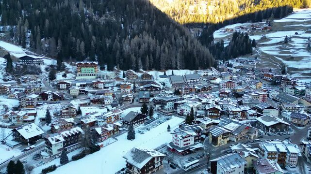Campitello di Fassa in winter transforms into a magical alpine retreat, nestled in the heart of the Dolomites. Snow-covered peaks, charming village architecture captured by drone