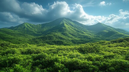 Fototapeta premium Lush green mountains under dramatic clouds with clear blue sky during midday