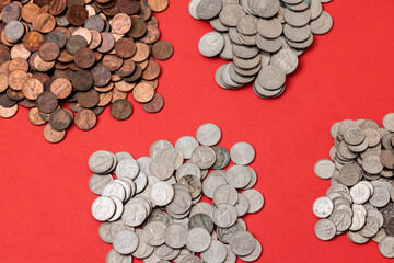 Assortment of copper and silver coins on red background.