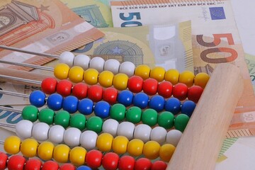 close up of a slide rule with colorful wooden balls lies on a stack of euro bills