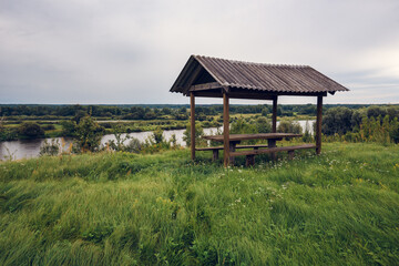 Wooden Gazebo on Riverbank Amid Natural Landscape — Rural Scene for Eco Themes and Vacation Design