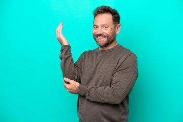 Fototapeta premium Middle age caucasian man isolated on blue background extending hands to the side for inviting to come