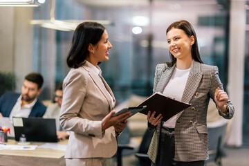 Two businesswoman working together in the office on their tablet.