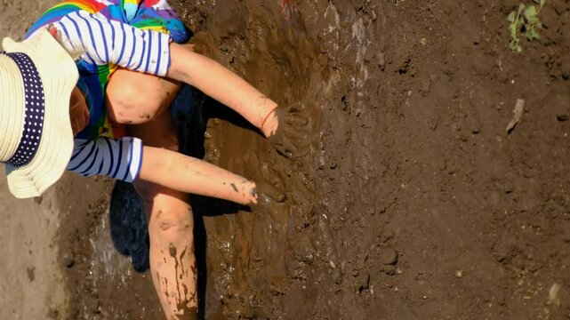 child dirty plays in mud. Selective focus.