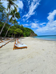 Blanca Beach and the blue waters of Culebra Bay, lush green trees, lounge chairs on the sandy beach, blue sky and clouds in Liberia Guanacaste Costa Rica