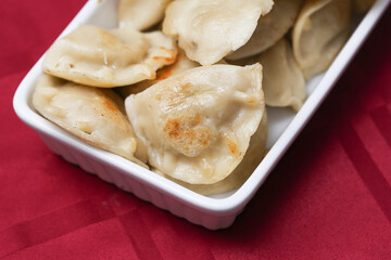 Traditional Polish dumplings on a festive Christmas table with a red tablecloth. Classic Christmas Eve dish with mushroom and cabbage filling. Iconic Eastern European holiday food Pierogi background.