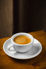 White cup of coffee on wooden table in the morning