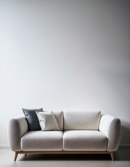 Cream-colored sofa with gray and off-white pillows against a white wall.