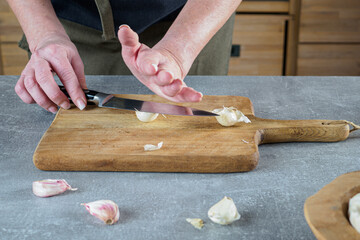 Peel garlic by classic crush method with knife. Overhead. © Jana Kollarova