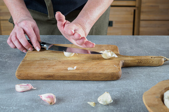 Peel garlic by classic crush method with knife. Overhead.